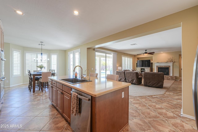 2514 E Grand Canyon Dr, Chandler, AZ 85249 - kitchen with stainless steel appliances, a glass covered fireplace, a kitchen island with sink, a ceiling fan, and light countertops
