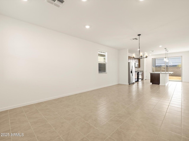 unfurnished living room featuring light tile patterned flooring, sink, and a notable chandelier