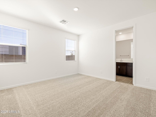 unfurnished bedroom featuring light colored carpet, connected bathroom, and sink