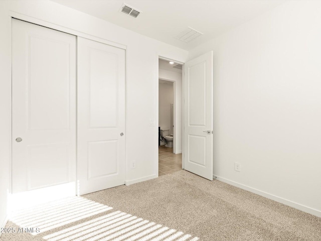 unfurnished bedroom with a closet and light carpet