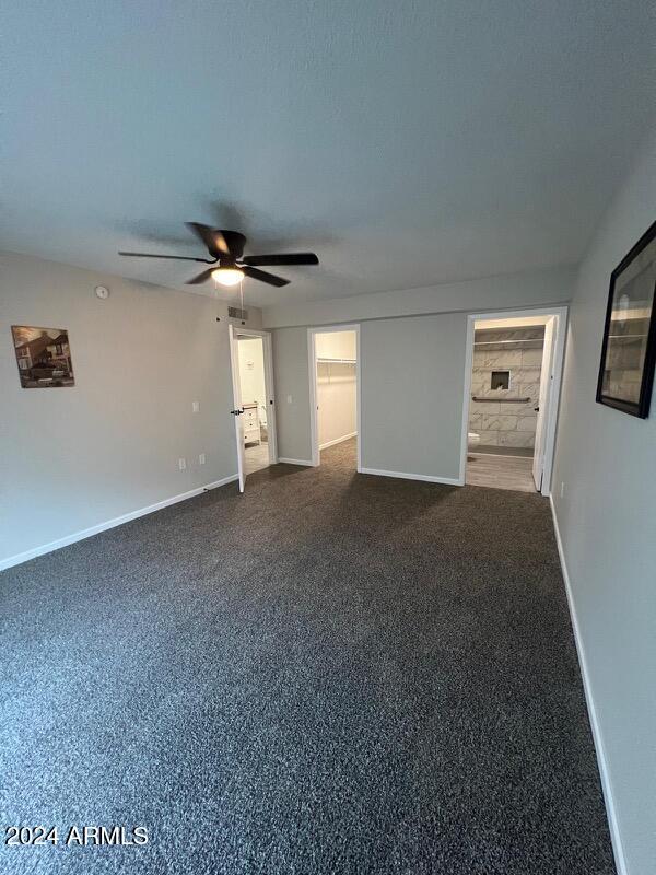 interior space with connected bathroom, ceiling fan, and carpet