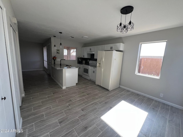 kitchen with white appliances, decorative light fixtures, white cabinetry, and an inviting chandelier