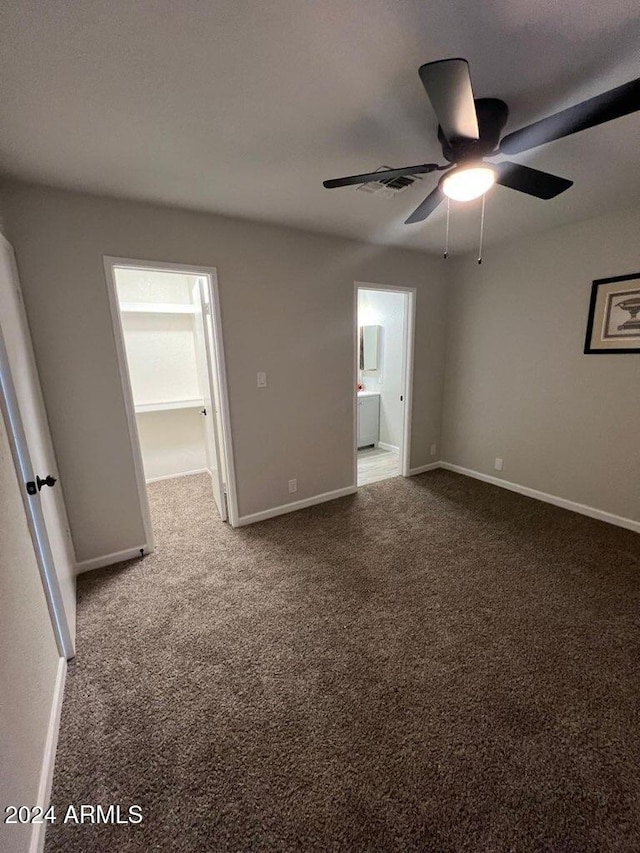 unfurnished bedroom with carpet flooring, ensuite bath, ceiling fan, and a spacious closet