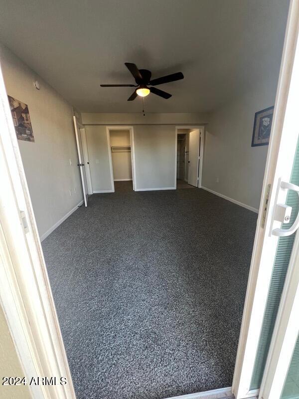 unfurnished bedroom with ceiling fan, a closet, and dark carpet