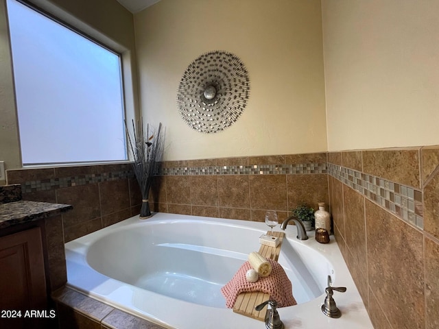 bathroom with vanity and tiled bath