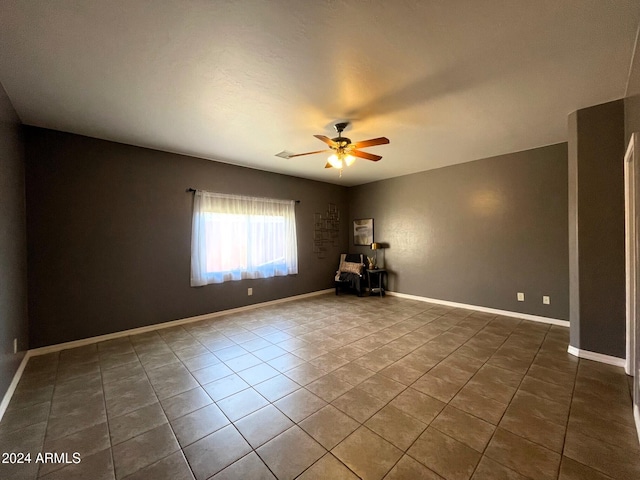 tiled spare room featuring ceiling fan