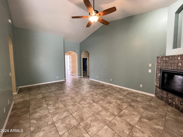 unfurnished living room with a tiled fireplace, ceiling fan, and high vaulted ceiling