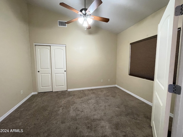 unfurnished bedroom with lofted ceiling, dark carpet, ceiling fan, and a closet