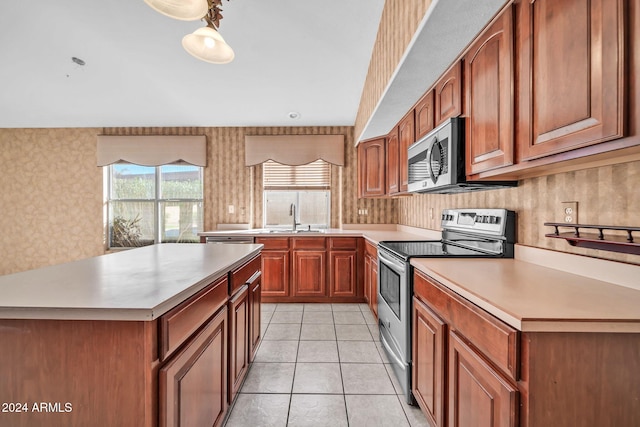 kitchen with light tile patterned floors, sink, decorative light fixtures, and appliances with stainless steel finishes