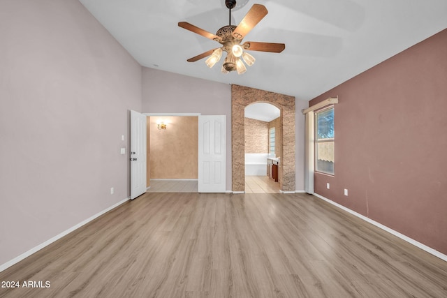 unfurnished bedroom with connected bathroom, light wood-type flooring, lofted ceiling, and ceiling fan