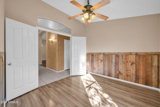 empty room with ceiling fan, vaulted ceiling, and light hardwood / wood-style floors