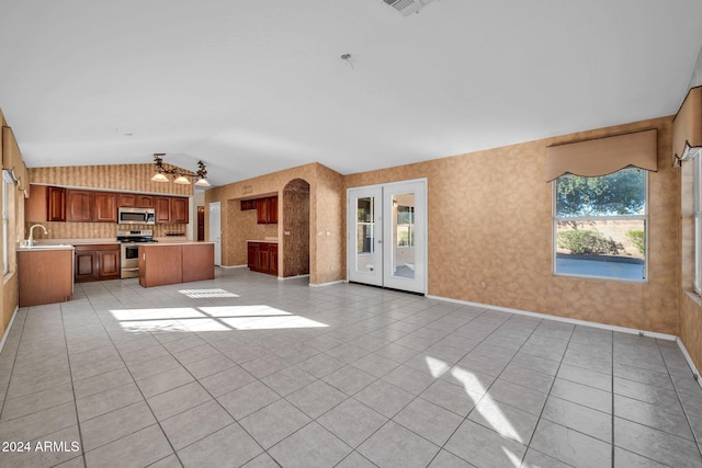 unfurnished living room with ceiling fan, sink, vaulted ceiling, and light tile patterned floors