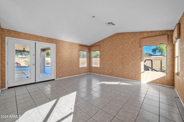 tiled spare room featuring french doors and lofted ceiling