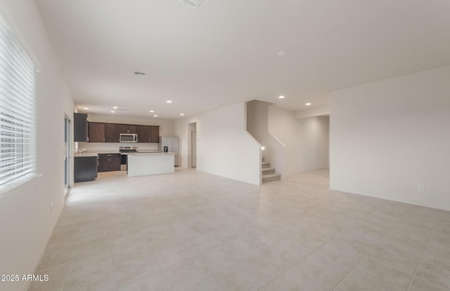 unfurnished living room with stairway, visible vents, and recessed lighting