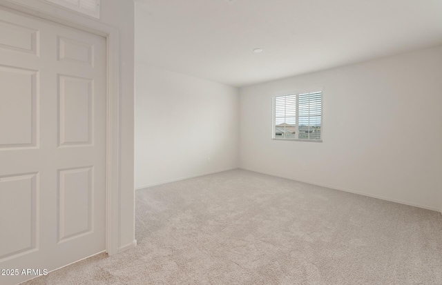 carpeted spare room featuring baseboards