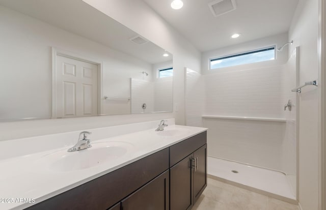 full bathroom featuring a sink, double vanity, and tiled shower