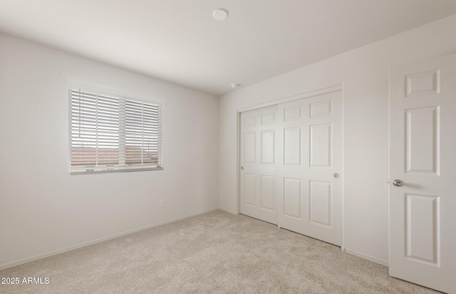 unfurnished bedroom with baseboards, carpet floors, and a closet