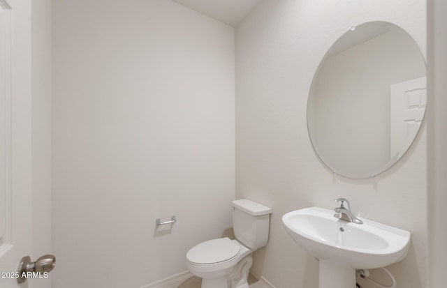 bathroom featuring toilet, a sink, and baseboards