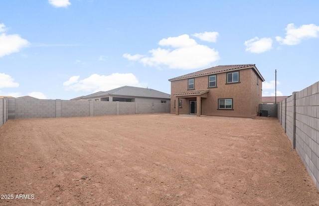 rear view of house featuring a fenced backyard, a tiled roof, central AC, and stucco siding