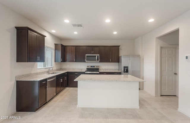 kitchen featuring dark brown cabinets, stainless steel appliances, a sink, and a kitchen island