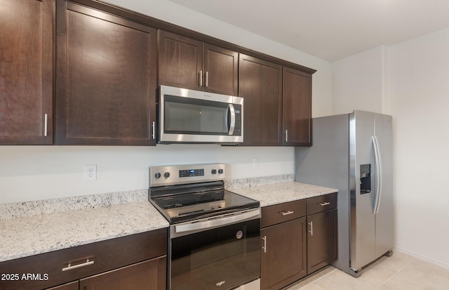 kitchen with light stone counters, stainless steel appliances, light tile patterned floors, baseboards, and dark brown cabinetry