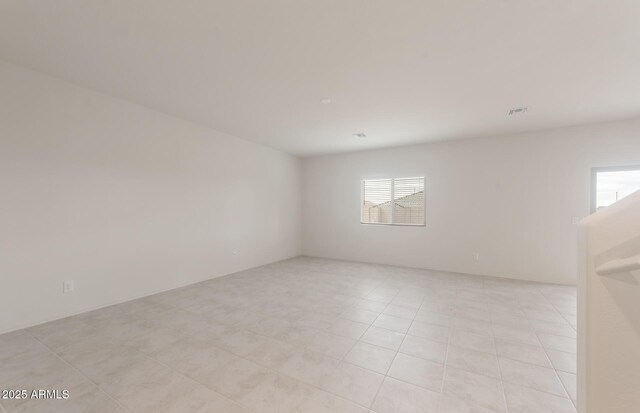 spare room with visible vents, a wealth of natural light, and light tile patterned floors