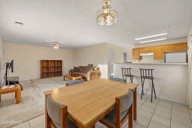 dining room with light tile patterned floors, light colored carpet, visible vents, and a ceiling fan