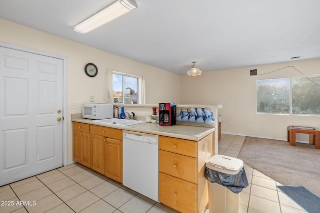 kitchen featuring light tile patterned floors, light countertops, light carpet, a sink, and white appliances