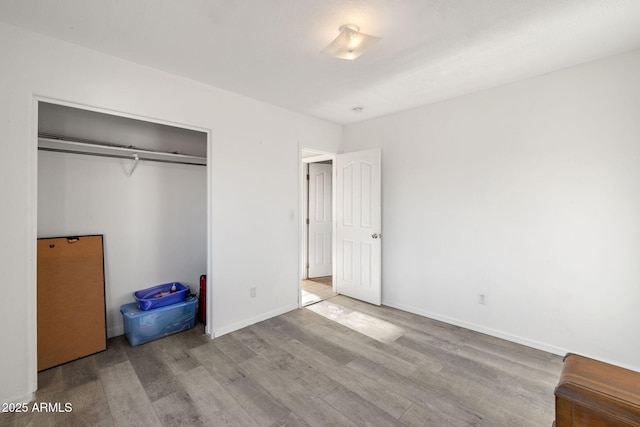 unfurnished bedroom with a closet, baseboards, and wood finished floors