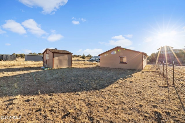 view of yard with a storage shed, fence, and an outbuilding