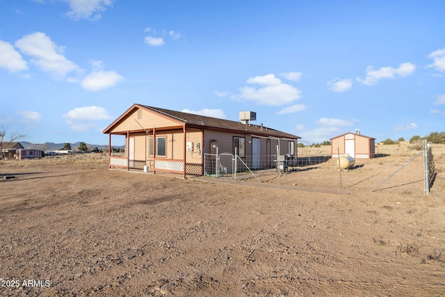 rear view of property featuring fence and an outdoor structure