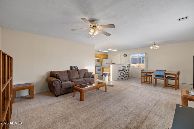 living area featuring light carpet, light tile patterned floors, visible vents, a ceiling fan, and a textured ceiling