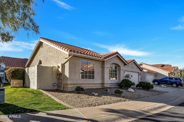 view of front of house featuring a garage, driveway, a tile roof, and stucco siding