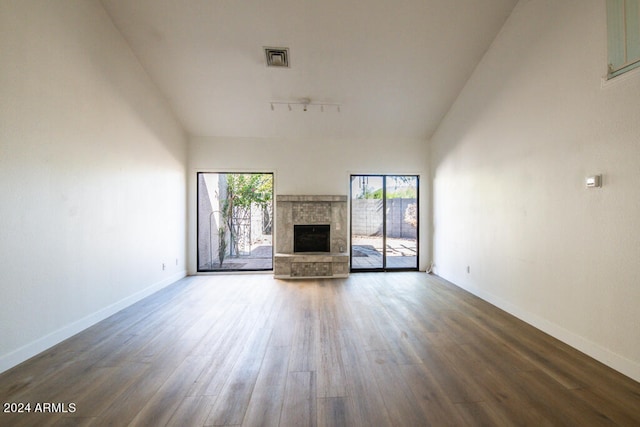 unfurnished living room featuring track lighting, dark hardwood / wood-style flooring, and vaulted ceiling