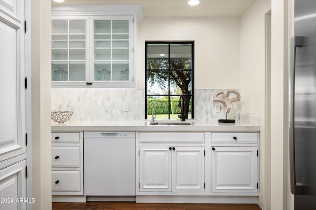 bar with decorative backsplash, white dishwasher, white cabinetry, and sink