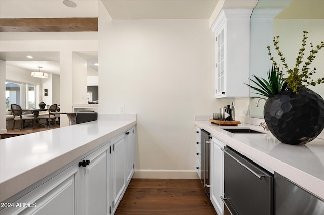 kitchen with dark hardwood / wood-style flooring, stainless steel dishwasher, sink, beamed ceiling, and white cabinets