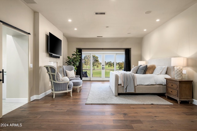 bedroom featuring access to outside, dark hardwood / wood-style flooring, french doors, and a barn door