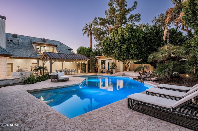 pool at dusk with a patio area