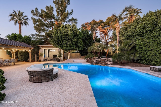 pool at dusk with outdoor lounge area and a patio area