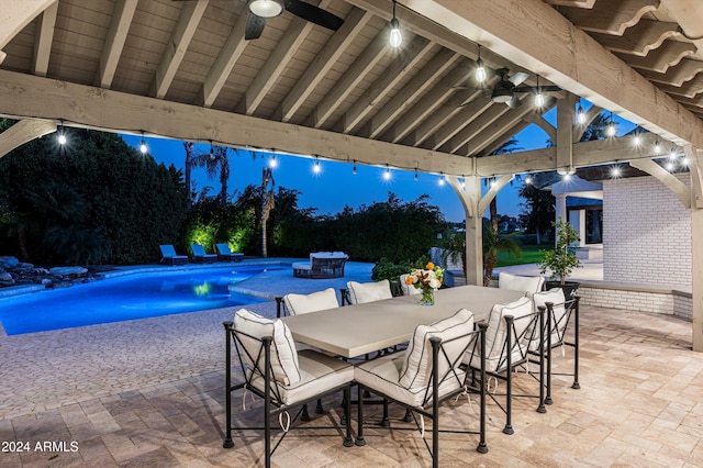 pool at night featuring a patio and ceiling fan