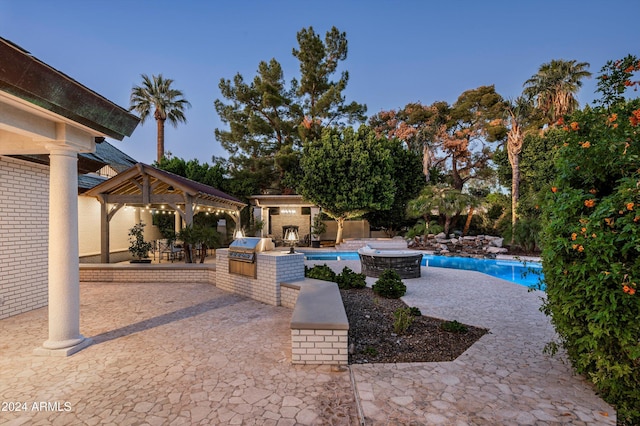 view of pool with a gazebo, an outdoor kitchen, a grill, and a patio