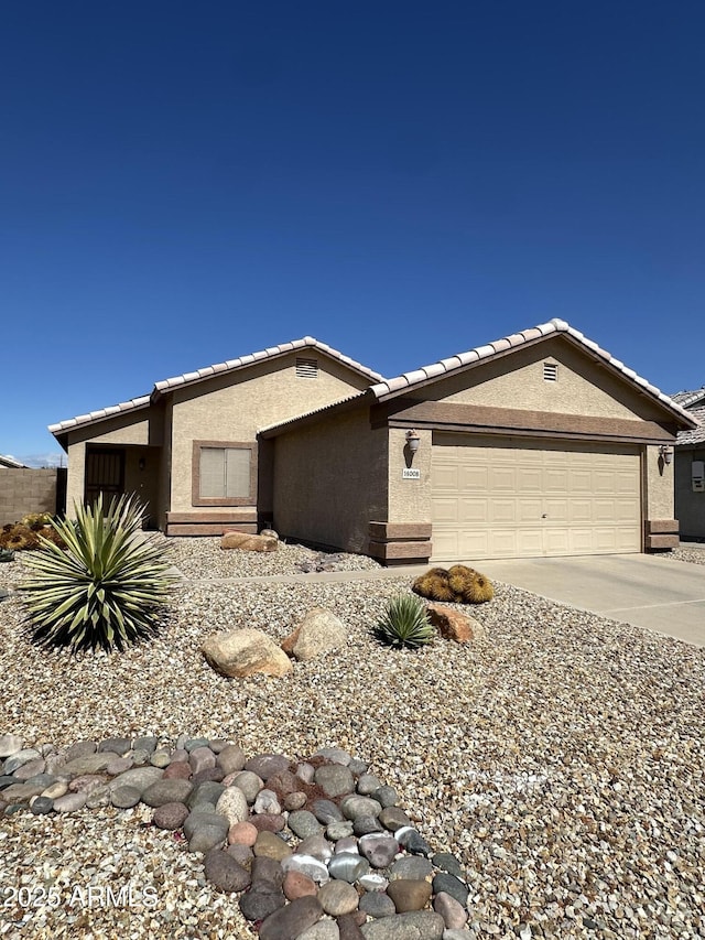 view of front facade with a garage, a tiled roof, concrete driveway, and stucco siding