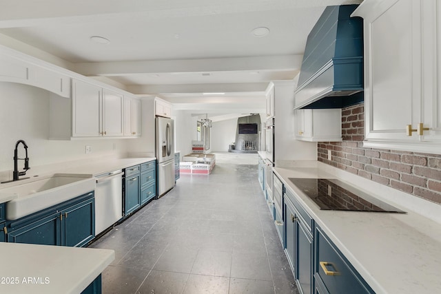 kitchen featuring custom range hood, white cabinets, stainless steel appliances, blue cabinets, and a sink