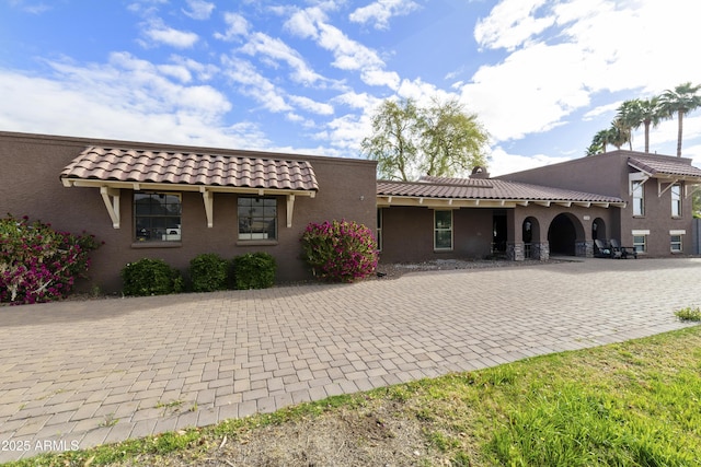 back of property with a tiled roof and stucco siding