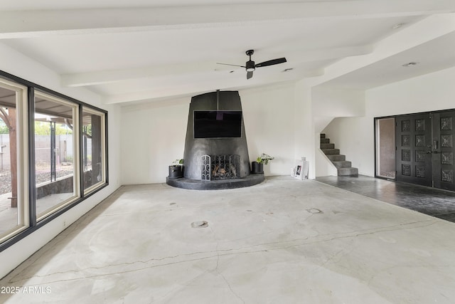 unfurnished living room with beamed ceiling, concrete flooring, and stairs