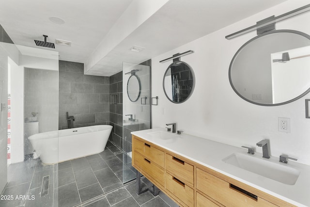 full bathroom featuring tile patterned flooring, a soaking tub, double vanity, and a sink