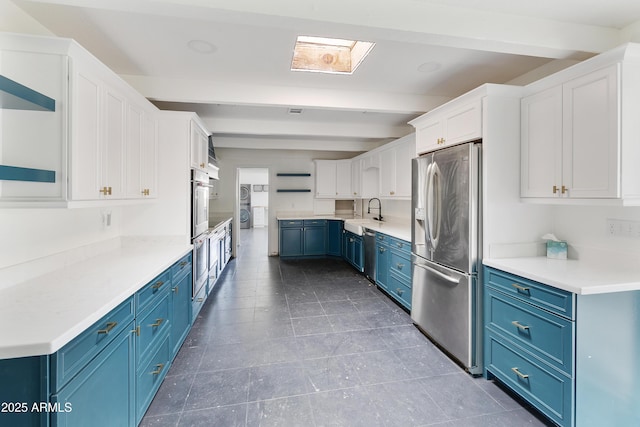 kitchen with open shelves, blue cabinetry, a sink, appliances with stainless steel finishes, and beamed ceiling