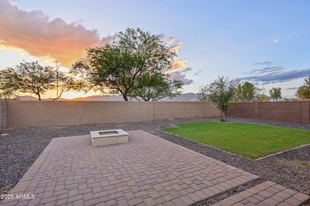 patio terrace at dusk featuring a yard and a fire pit