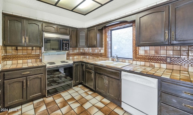 kitchen featuring backsplash, dark brown cabinetry, tile counters, and white appliances