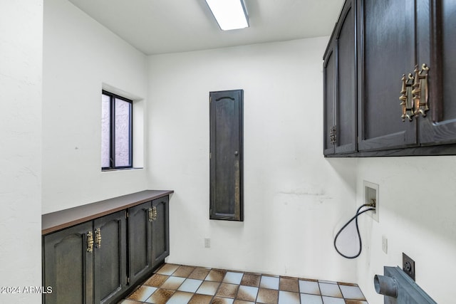 clothes washing area featuring electric dryer hookup and cabinets